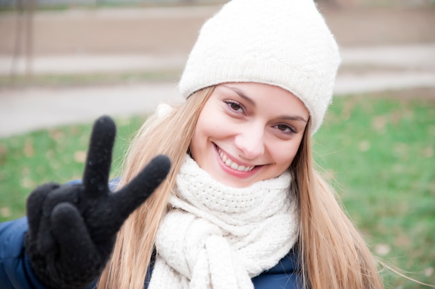 Concepto de la gente feliz - mujer joven que muestra la victoria o el signo de la paz