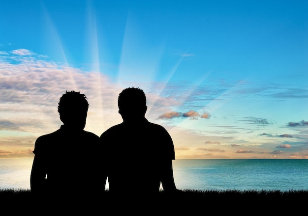 Concepto de gente gay. Silueta de dos hombres gay descansando sobre un fondo de cielo y mar azul