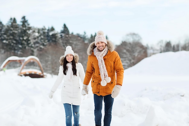 concepto de gente, temporada, amor y ocio - pareja feliz caminando sobre fondo de invierno