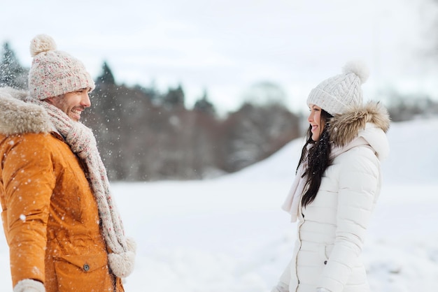 concepto de gente, temporada, amor y ocio - pareja feliz caminando sobre fondo de invierno