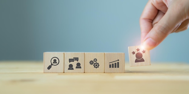 Concepto de gestión de recursos humanos El gerente sostiene el cubo con el icono del personal ascendido y el icono de la etapa de gestión de los recursos humanos en los cubos La capacitación de reclutamiento La gestión del rendimiento La recompensa con fondo azul