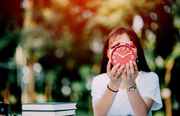 Foto concepto de gestión del tiempo del despertador rojo las manos femeninas ajustan o cambian la hora del reloj para trabajar