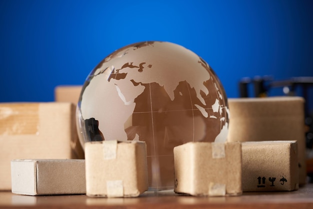 Concepto global de envío y logística globo de vidrio rodeado de cartón marrón