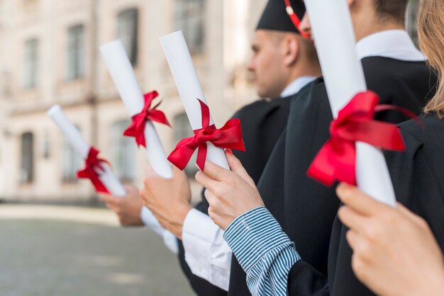 Foto concepto de graduación con estudiantes sujetando sus diplomas