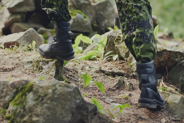 Foto concepto de guerra, caminatas, ejército y personas - cerca de las piernas de los soldados escalando rocas en el bosque