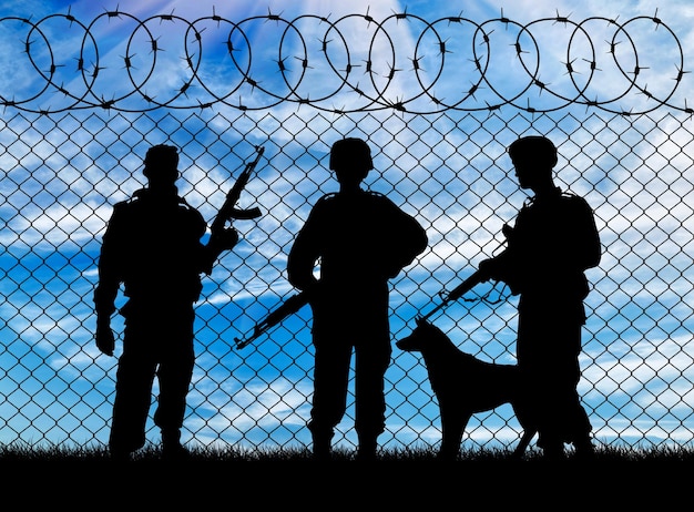 Concepto de guerra. Silueta de los militares cerca de la frontera con el perro en el fondo del cielo