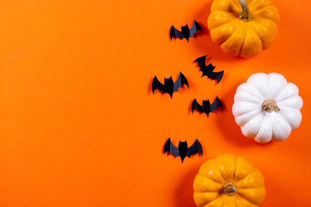 Concepto de halloween. Bandada de murciélagos de papel negro y calabaza fresca sobre fondo de papel naranja.