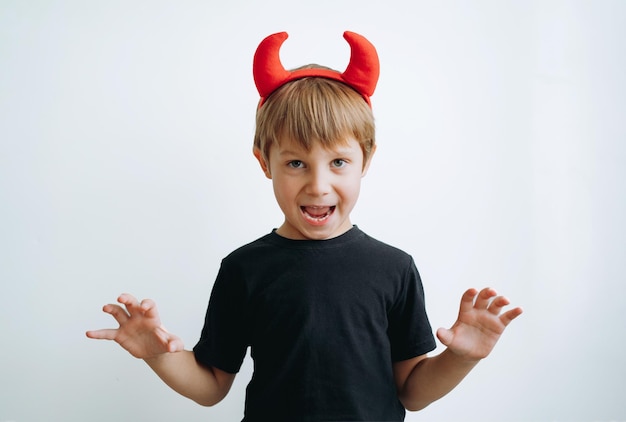 Concepto de Halloween lindo niño con cuernos de diablo rojo aislado sobre fondo blanco.