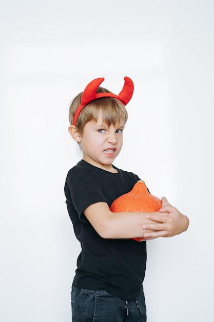 Concepto de Halloween lindo niño con cuernos de diablo rojo aislado sobre fondo blanco.