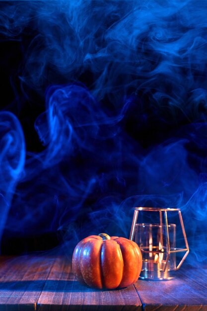 Concepto de Halloween Linterna de calabaza naranja sobre una mesa de madera oscura con humo de doble color alrededor del truco o trato de fondo de cerca