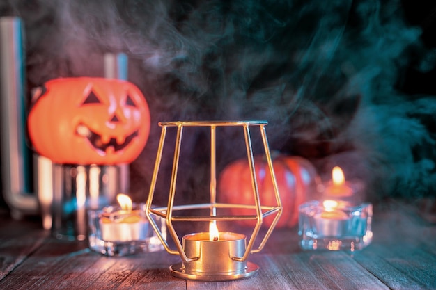 Concepto de Halloween linterna de calabaza naranja y velas en una mesa de madera oscura con humo de color naranja verde alrededor del truco o trato de fondo de cerca