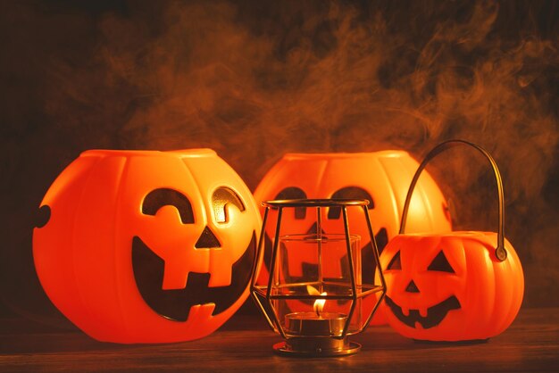 Foto concepto de halloween linterna de calabaza de plástico naranja con cara de risa en una mesa de madera oscura con humo alrededor del truco o trato de fondo de cerca