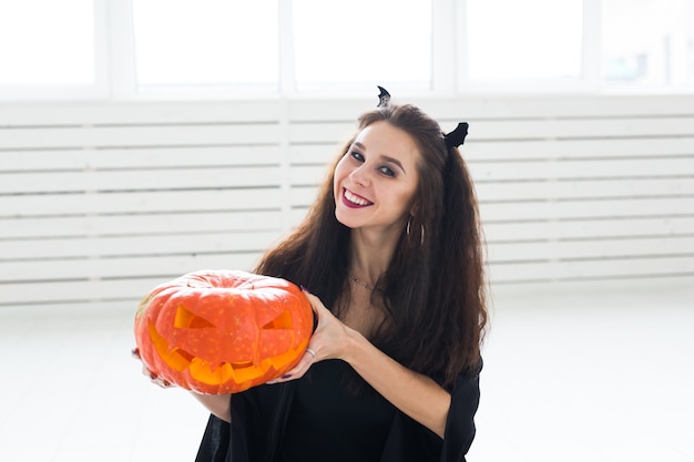 Concepto de Halloween y mascarada - Hermosa mujer joven posando con calabaza Jack-o'-lantern.