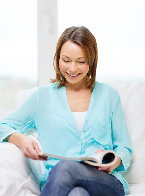 concepto de hogar y ocio - mujer sonriente leyendo revista en casa