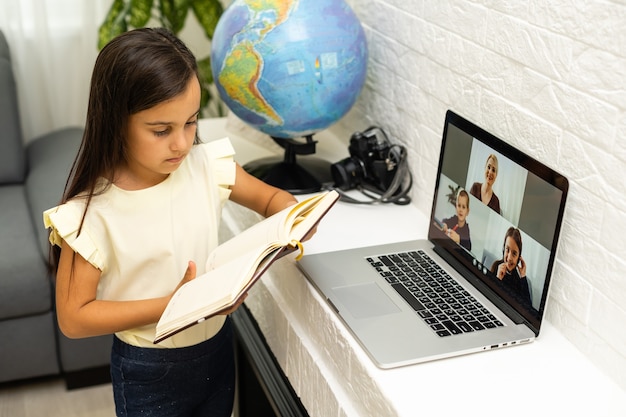 concepto de hogar, ocio, tecnología e internet - niña estudiante con computadora portátil en casa, niña usa video chat