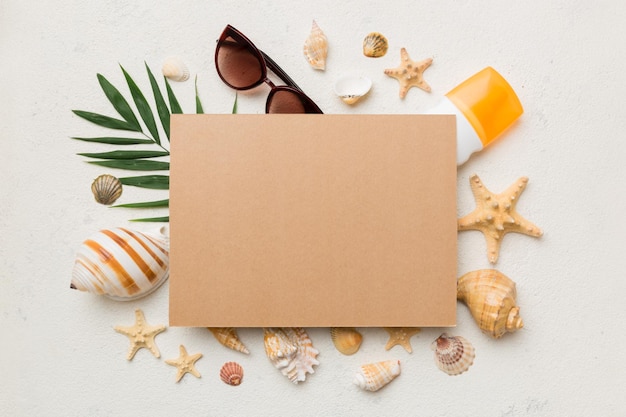 Concepto de horario de verano con tarjeta de felicitación en blanco y papel artesanal en blanco sobre fondo de color Conchas marinas de la costa del océano en forma de marco separado con espacio para la vista superior de texto