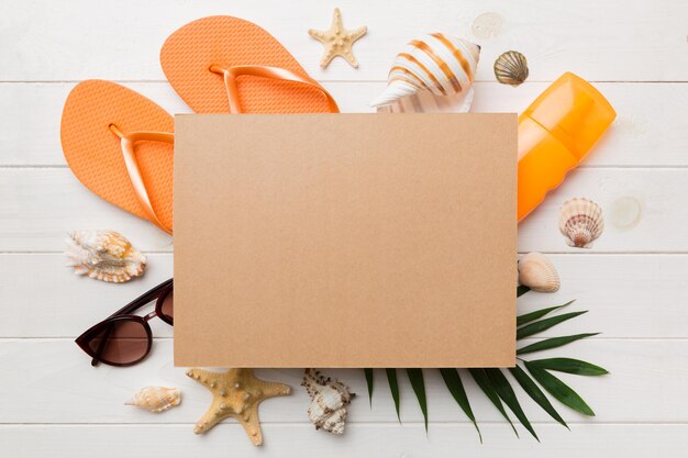 Concepto de horario de verano con tarjeta de felicitación en blanco y papel artesanal en blanco sobre fondo de color Conchas marinas de la costa del océano en forma de marco separado con espacio para la vista superior de texto