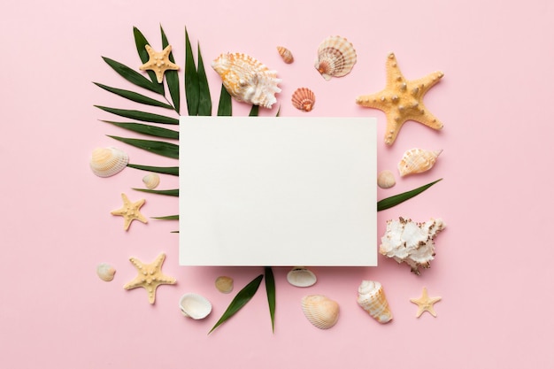 Foto concepto de horario de verano con tarjeta de felicitación en blanco y papel blanco en blanco sobre fondo de color conchas marinas de la costa del océano en forma de marco separado con espacio para la vista superior de texto