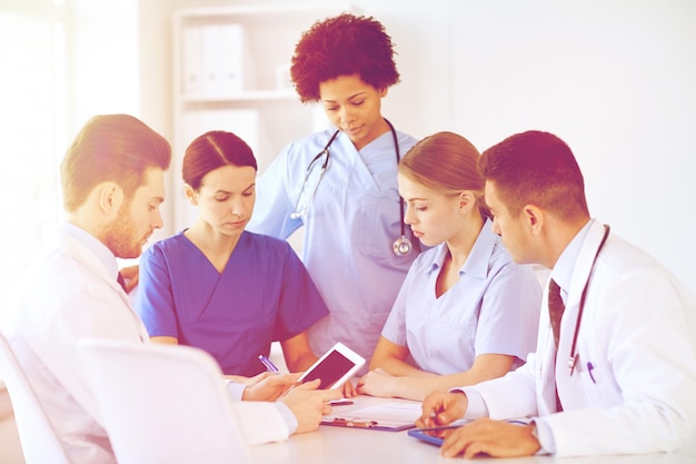 Foto concepto de hospital, profesión, personas y medicina - grupo de médicos con tabletas reunidas en el consultorio médico