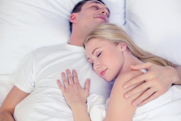 concepto de hotel, viajes, relaciones y felicidad - pareja feliz durmiendo en la cama