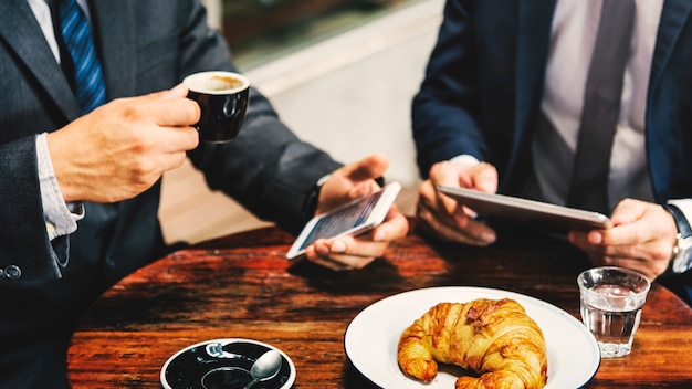 Concepto inalámbrico de la tableta de la reunión del café de dos hombres de negocios