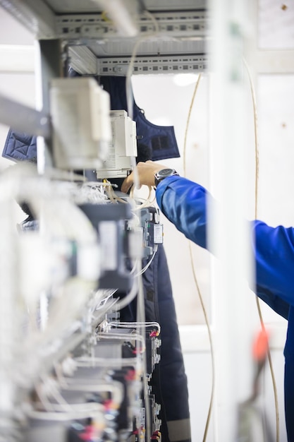 Concepto industrial. Un hombre de pie junto a los paneles de control. Tiro vertical