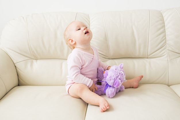 concepto de infancia, infancia y personas - niña feliz sentada en el sofá en casa