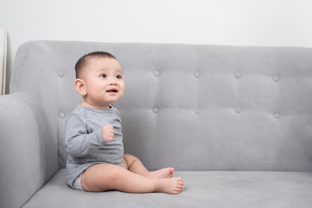 Concepto de infancia, infancia y personas - niña feliz sentada en el sofá en casa