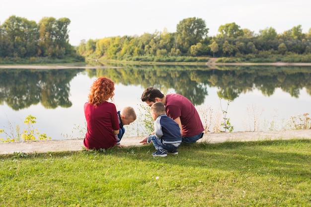 Concepto de infancia y naturaleza - Familia con hijos pequeños sentados en la hierba verde.