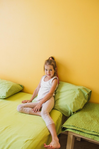 El concepto de infancia. El niño se sienta pensativo en la cama del dormitorio amarillo.