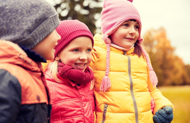 concepto de infancia, ocio, amistad y personas - grupo de niños felices abrazándose en el parque de otoño