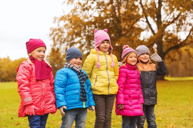 concepto de infancia, ocio, amistad y personas - grupo de niños felices en el parque de otoño