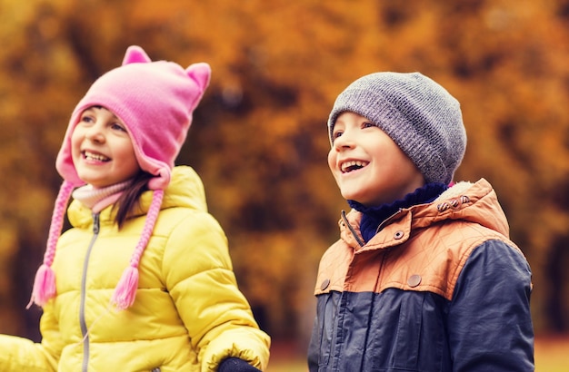 concepto de infancia, ocio, amistad y personas - grupo de niños felices en el parque de otoño