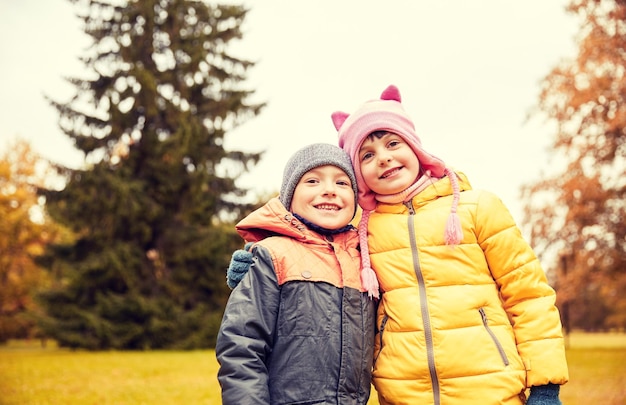 concepto de infancia, ocio, amistad y personas - niña y niño felices en el parque de otoño