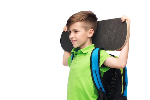 Foto concepto de infancia, ocio, escuela y personas - feliz estudiante sonriente con mochila y monopatín