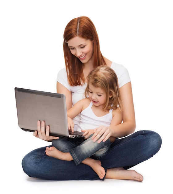 concepto de infancia, paternidad y tecnología - madre feliz con una niña adorable con laptop