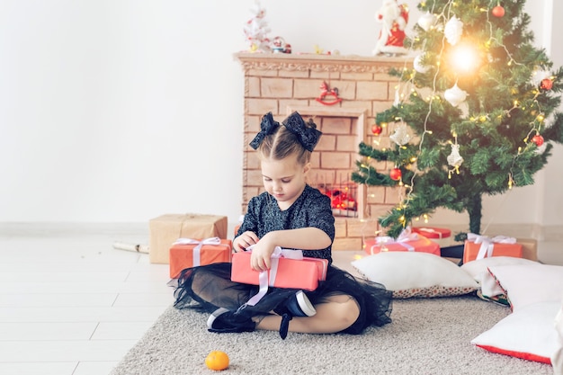 Concepto de infancia y vacaciones - Retrato de niña linda feliz con regalo de Navidad