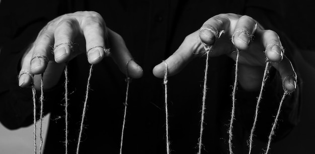 Concepto de influencia y manipulación Manos de hombre con cuerdas en los dedos para controlar el abuso