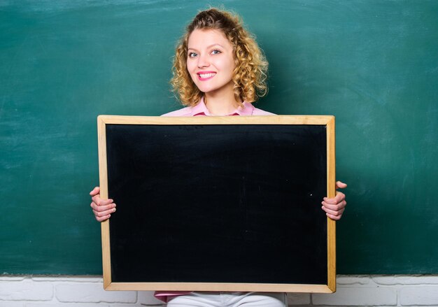 Foto concepto de información escolar noticias de última hora información sobre el horario de la campana de la escuela recuerde esta información información sobre tareas domésticas informar a los alumnos profesor mujer alegre sostener pizarra espacio en blanco