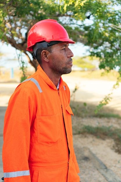 Concepto de ingeniero o técnico. Mecánico de sexo masculino africano en uniforme anaranjado que mira en la distancia.