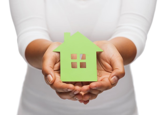 concepto inmobiliario y ecológico - imagen de primer plano de las manos de una mujer sosteniendo una casa verde
