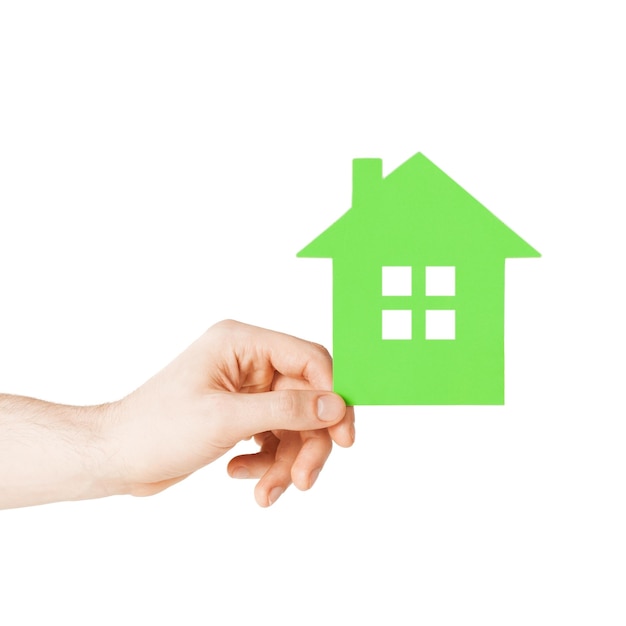 concepto inmobiliario y de hogar familiar - imagen de primer plano de la mano masculina sosteniendo una casa de papel verde