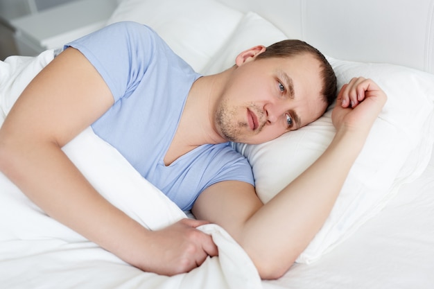 Foto concepto de insomnio - retrato de hombre cansado acostado en la cama en su casa