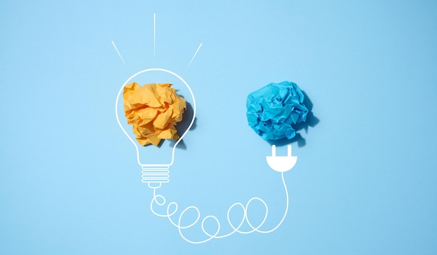 El concepto de inspiración con nuevas ideas, la búsqueda de soluciones creativas, hojas de papel arrugadas en forma de bolas sobre un fondo azul.