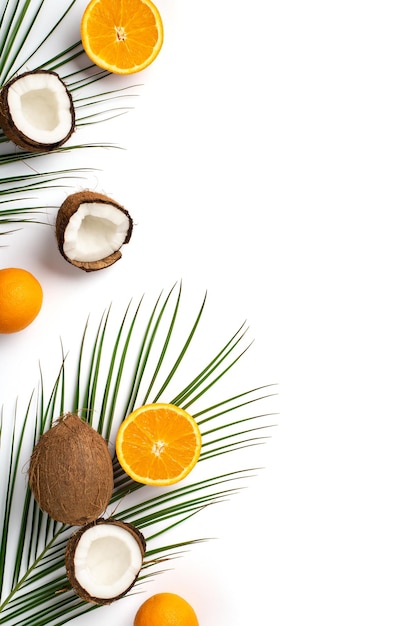 Concepto de inspiración de verano Foto vertical de vista superior de frutas tropicales frescas, cocos agrietados, naranjas cortadas y hojas de palma sobre fondo blanco aislado con espacio de copia