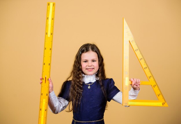 Concepto inteligente e inteligente Dimensionamiento y medición Alumno linda chica con regla grande Estudiante de escuela estudia geometría Niño uniforme escolar sostiene regla Me encantan las matemáticas Concepto de educación y escuela