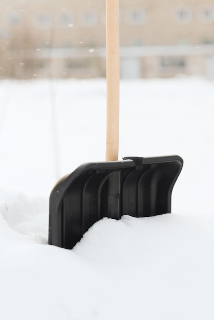 concepto de invierno y equipo - Snowshowel negro con mango de madera en la pila de nieve