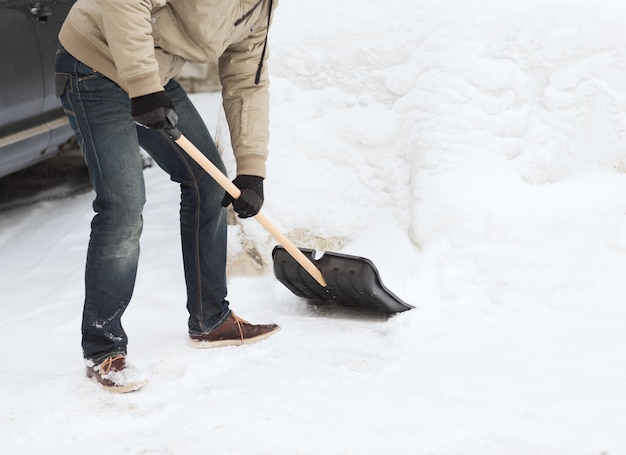 concepto de invierno y limpieza - cierre del hombre quitando nieve de la calzada
