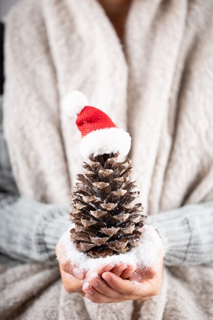 Concepto de invierno Manos jovenes que sostienen la decoración de la Navidad. Idea de decoración navideña. Decoración navideña en manos de una mujer, fondo con bokeh dorado.