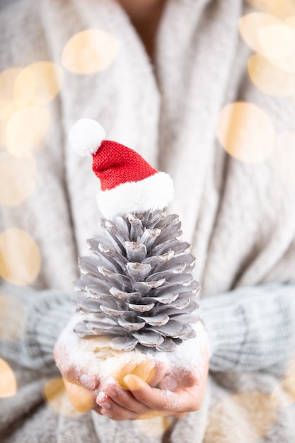 Concepto de invierno Manos jóvenes sosteniendo la decoración de Navidad. Idea de decoración navideña. Decoración navideña en manos de una mujer, fondo con bokeh dorado.